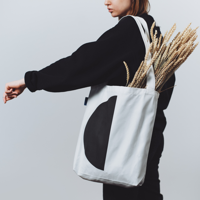 Stylish eco-friendly tote bag with minimalist design, worn by a woman in black outfit